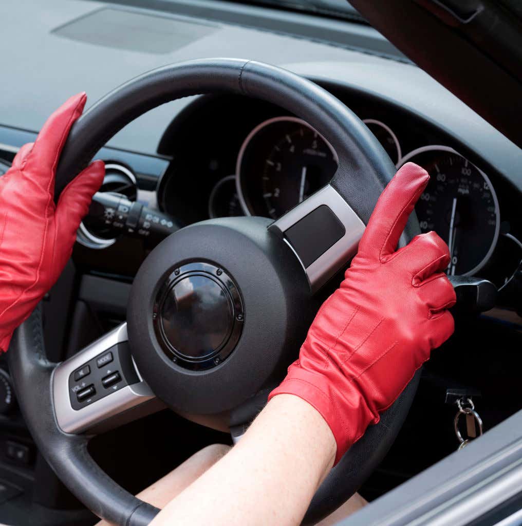 红色皮革驾驶手套放在方向盘上。