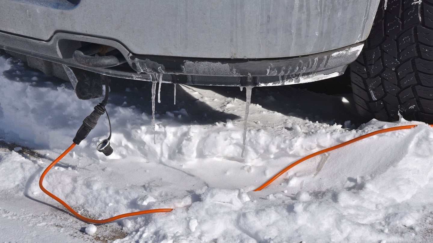 一辆车停在雪地里，发动机缸体加热器还插着电。