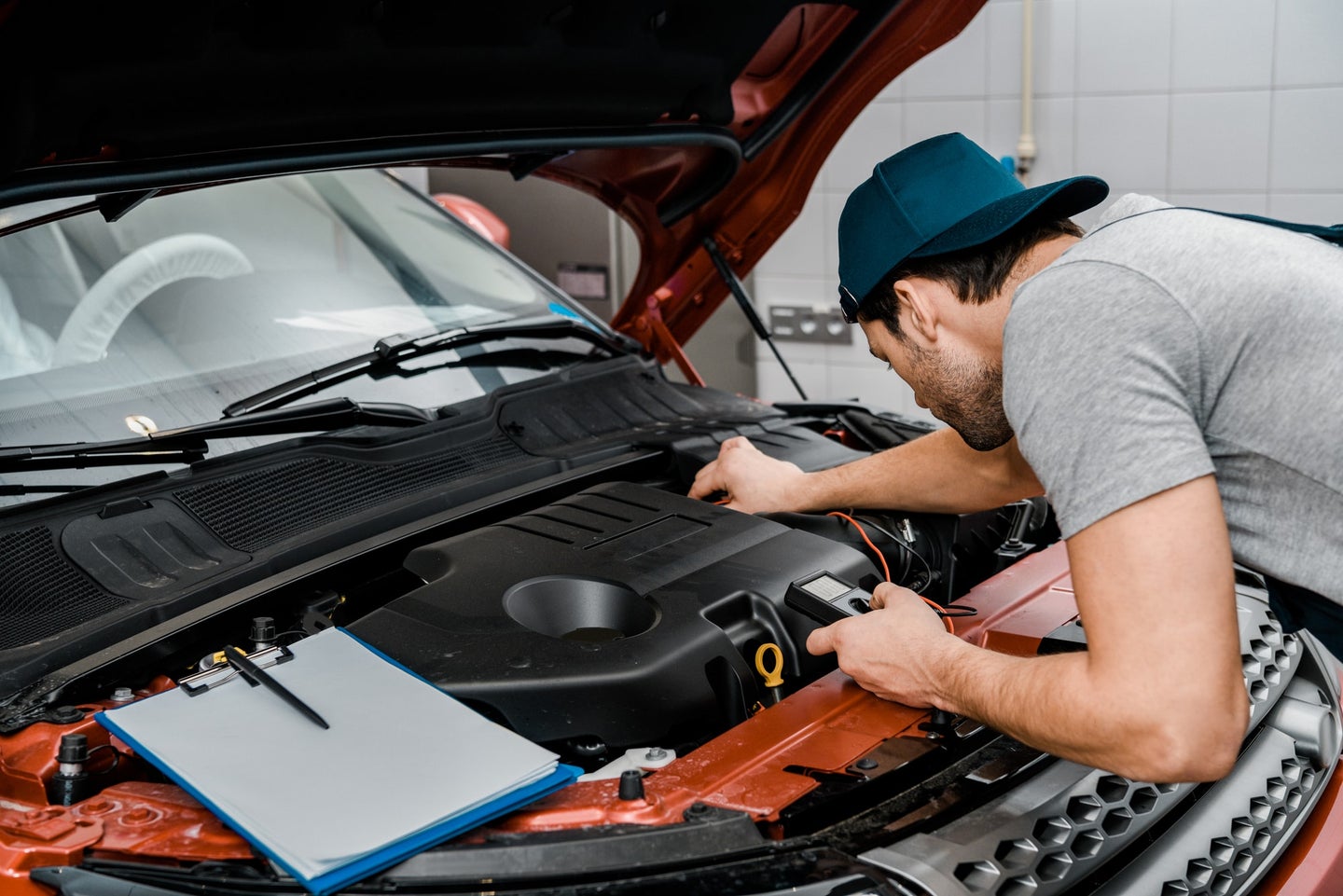 汽车修理工在修车车间用万用表电压表检查汽车电池电压
